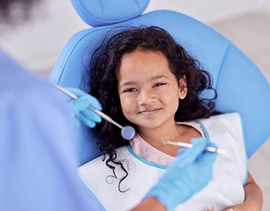 Young girl smiling while sitting in dentist's treatment chair