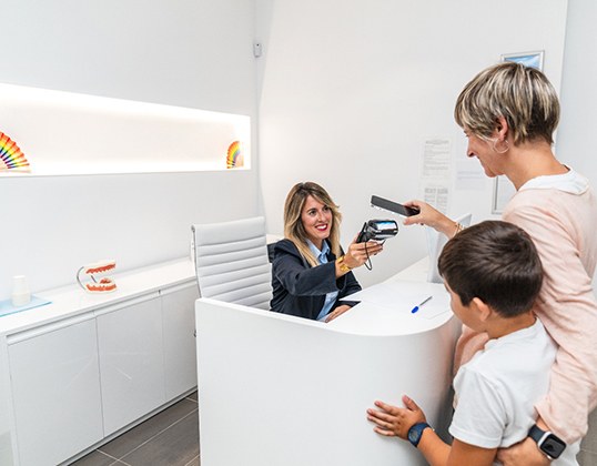 Mother paying for her child’s dental care at front desk