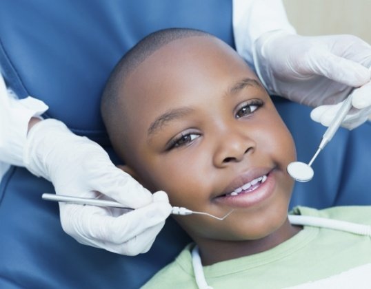 Pediatric dentist examining child after all ceramic dental restorations