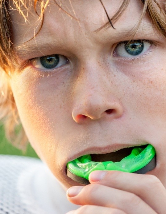 Teen placing a custom athletic mouthguard