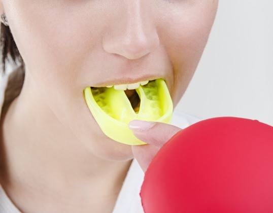 Closeup of teen placing an athletic mouthguard