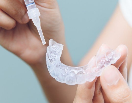 Young dental patient using at home teeth whitening kit