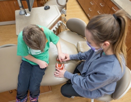 Pediatric dental team member giving child at home hygiene tips