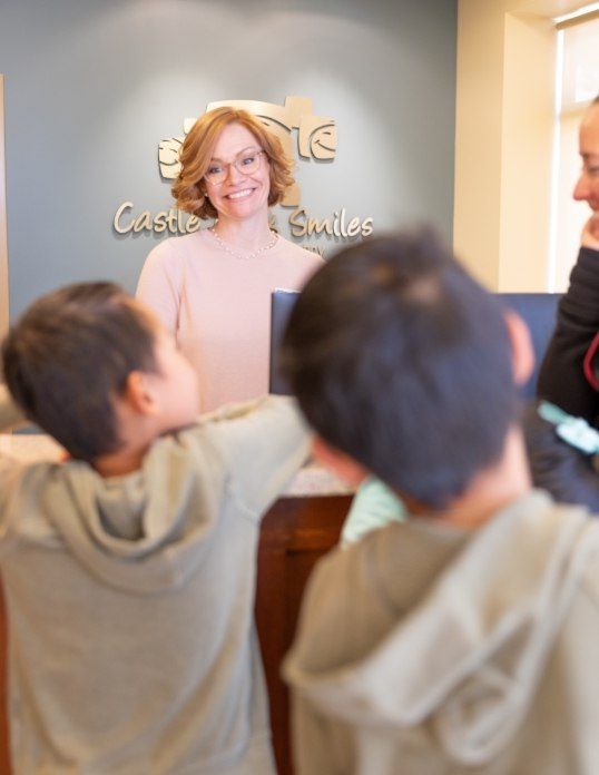 Friendly pediatric dental team member smiling at family