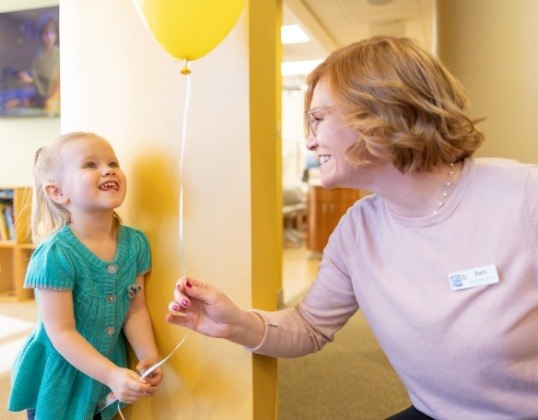 Friendly pediatric dental team member giving dentistry patient a balloon