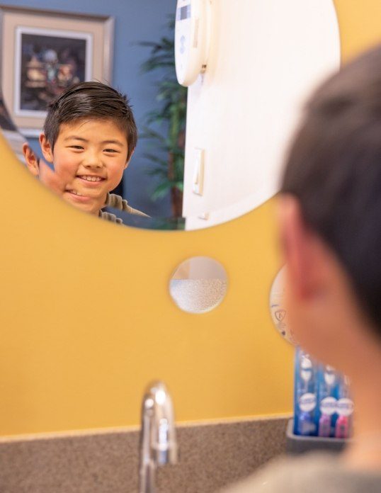 Child looking at smile in mirror during emergency dentistry visit