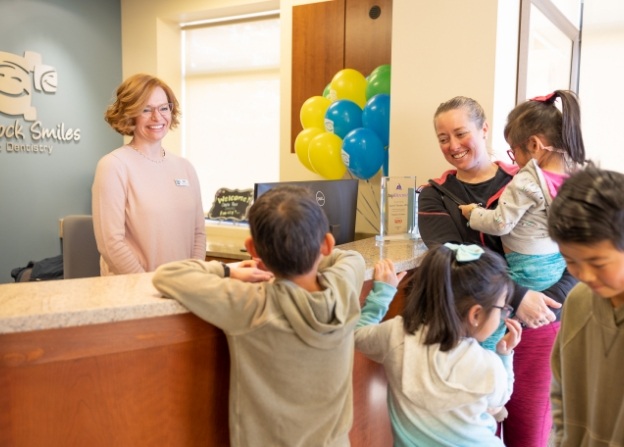 Friendly pediatric dental team member greeting dentistry patient