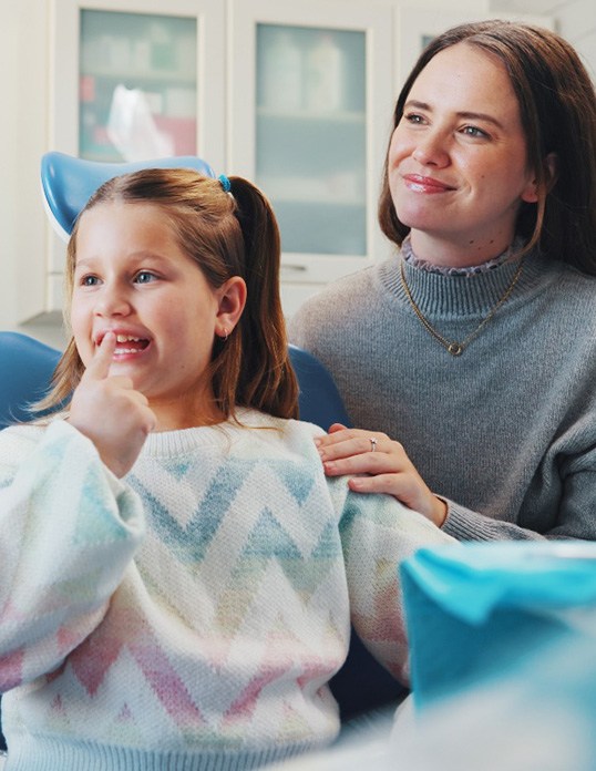 Happy young girl talking to her dentist