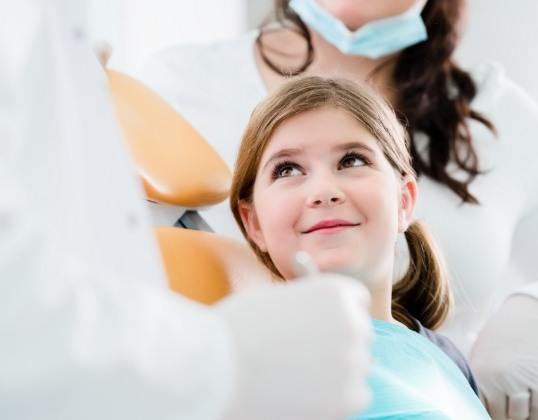 Child smiling at dentist during oral cancer screening