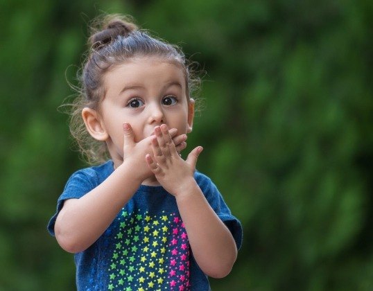 Child covering mouth before pediatric tooth extraction