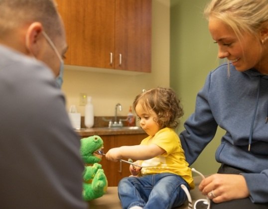 Child and parent talking to pediatric dentist at first dental appointment