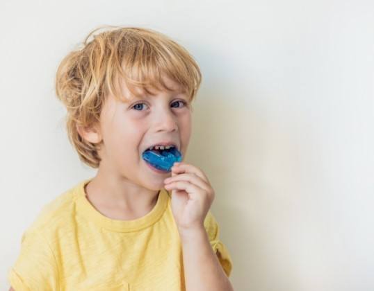 Child placing an athletic mouthguard