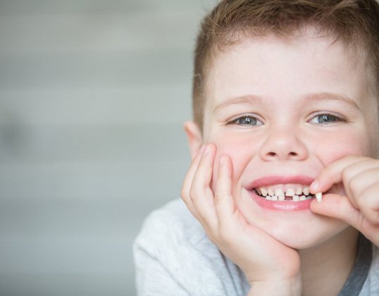 Child holding a tooth that has fallen out