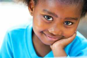 smiling child holding face blue shirt