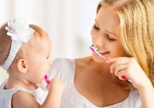 Mother and her child brushing their teeth