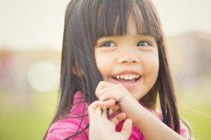young girl smiling rubbing hair