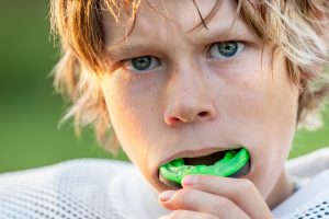 young boy blonde hair green mouthguard