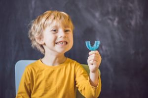 Little boy in yellow shirt holding a sports mouthguards for children