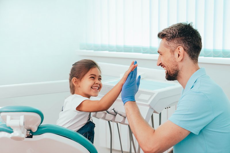 a little girl giving her dentist a high-five after a good appointment