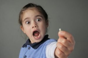 Girl holding tooth shocked at losing baby teeth