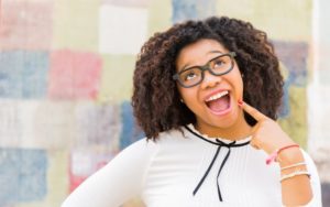 Teenager points to her smile after visiting her pediatric dentist