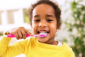 smiling little girl brushing her teeth for better oral health