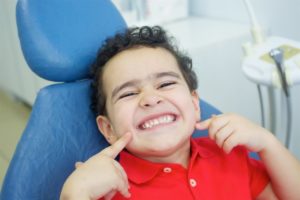 Smiling boy points to his new dental sealants for children