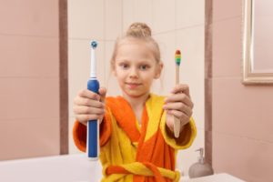 young girl using electric toothbrush