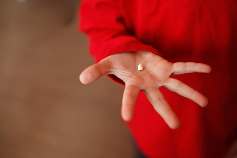 child holding lost tooth in hand