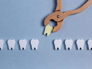 Wooden tooth being pulled out of a row by toy wooden forceps