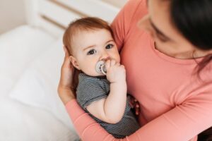 Parents holding her infant who's using a pacifier