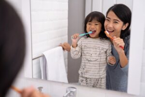 Child and mom brushing their teeth together