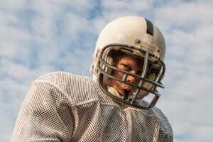 Young football player in uniform wearing mouthguard.